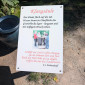 Ein Schild im Freien mit der Überschrift „Klangsäule“. Darauf steht eine Anleitung, wie man durch Reiben eines mit Wasser benetzten Granitblocks Klänge erzeugen kann. In der Mitte ist ein Foto von Menschen, die gemeinsam an der Klangsäule stehen. Darunter befindet sich ein Gedicht von Joseph von Eichendorff.